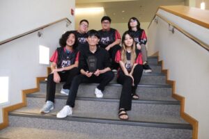 Pueo Gaming League of Legends team members with their championship trophy, front row from left to right, Trey Lum, Micah Murakami (team coach), and Melanie Denda, and back row from left to right, Cyrus Olivas, Joshua Sato, and Ari Nicholson. Image courtesy of UHWO Staff